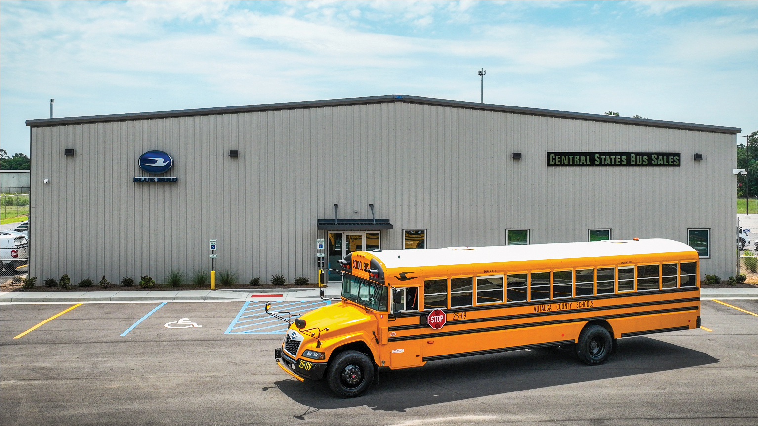 Yellow school bus parked in front of a gray Central States Bus Sales building