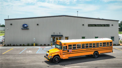 Yellow school bus parked in front of a gray Central States Bus Sales building