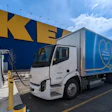 White electric delivery truck charging at IKEA store with blue and yellow building