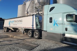 Blue and white semi-truck from Thomas E. Keller Trucking parked near industrial storage silos
