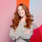 Smiling woman with wavy auburn hair in spotted blouse against colorful background Headshot