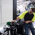 Worker in safety vest checking truck tire in industrial manufacturing facility