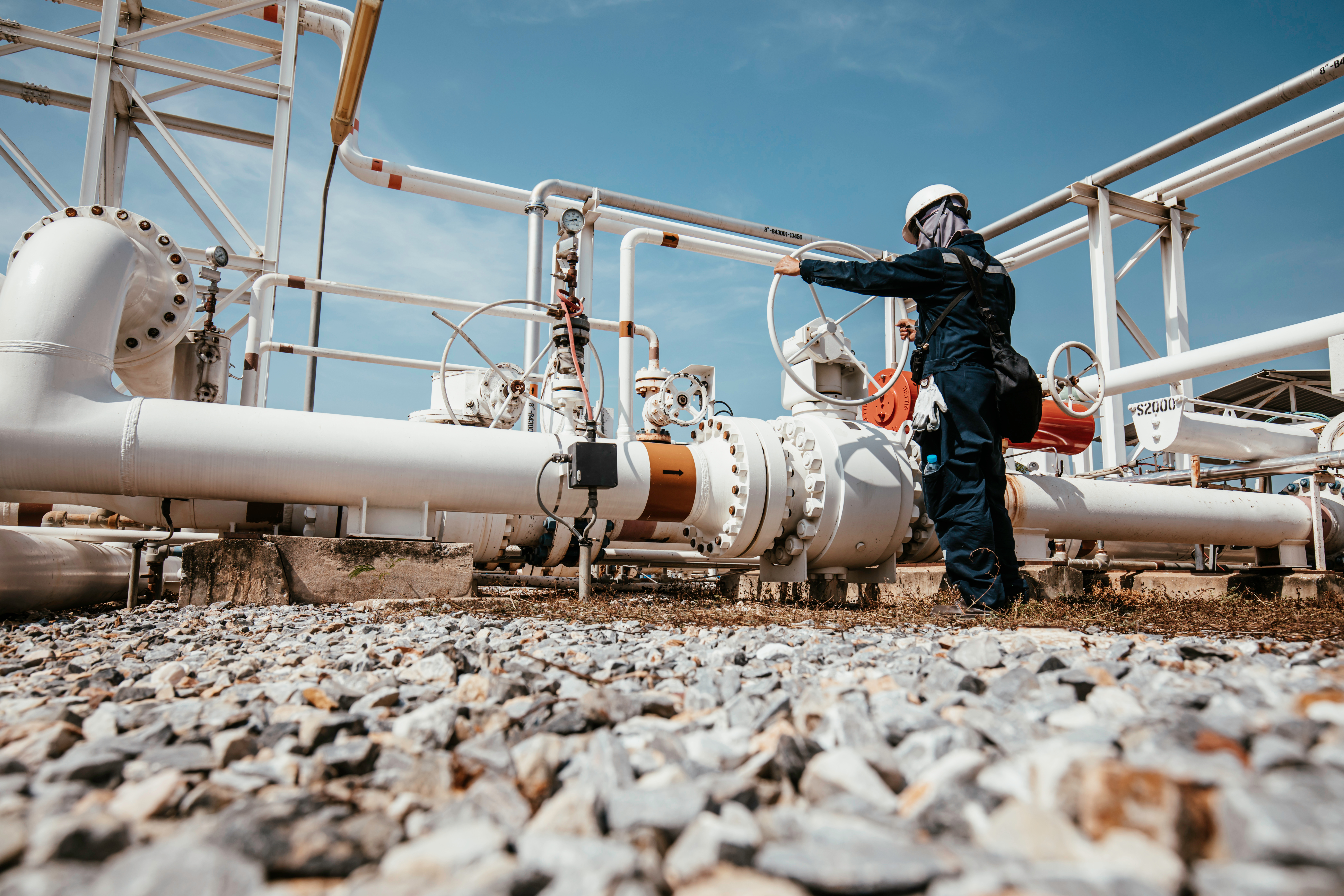 Industrial worker inspecting pipeline valves at oil and gas facility