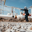 Industrial worker inspecting pipeline valves at oil and gas facility