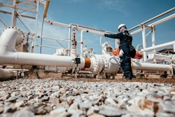 Industrial worker inspecting pipeline valves at oil and gas facility