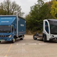 Blue Mitsubishi Fuso delivery truck parked next to a white electric delivery vehicle