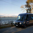 Amazon Prime delivery van parked by a scenic lake with autumn trees