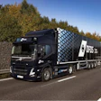 Black DFDS semi-truck driving on highway with autumn trees in background