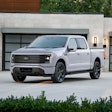 White Ford F-150 Lightning electric pickup truck parked in front of modern garage