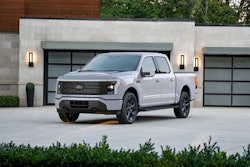 White Ford F-150 Lightning electric pickup truck parked in front of modern garage
