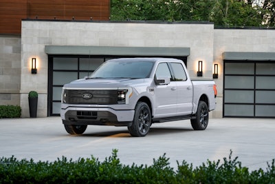 White Ford F-150 Lightning electric pickup truck parked in front of modern garage
