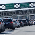 Traffic queued at United States border crossing with lane guidance signs