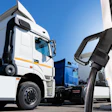 White semi-truck being refueled at a truck depot with blue sky background