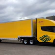 Yellow DHL semi-truck and trailer parked on asphalt with cloudy sky background