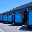 Amazon delivery vans lined up at logistics center under blue sky