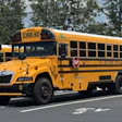 Yellow school bus parked on road with trees in background