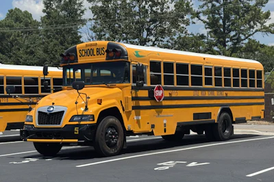 A yellow battery-electric school bus built by Blue Bird is parked.