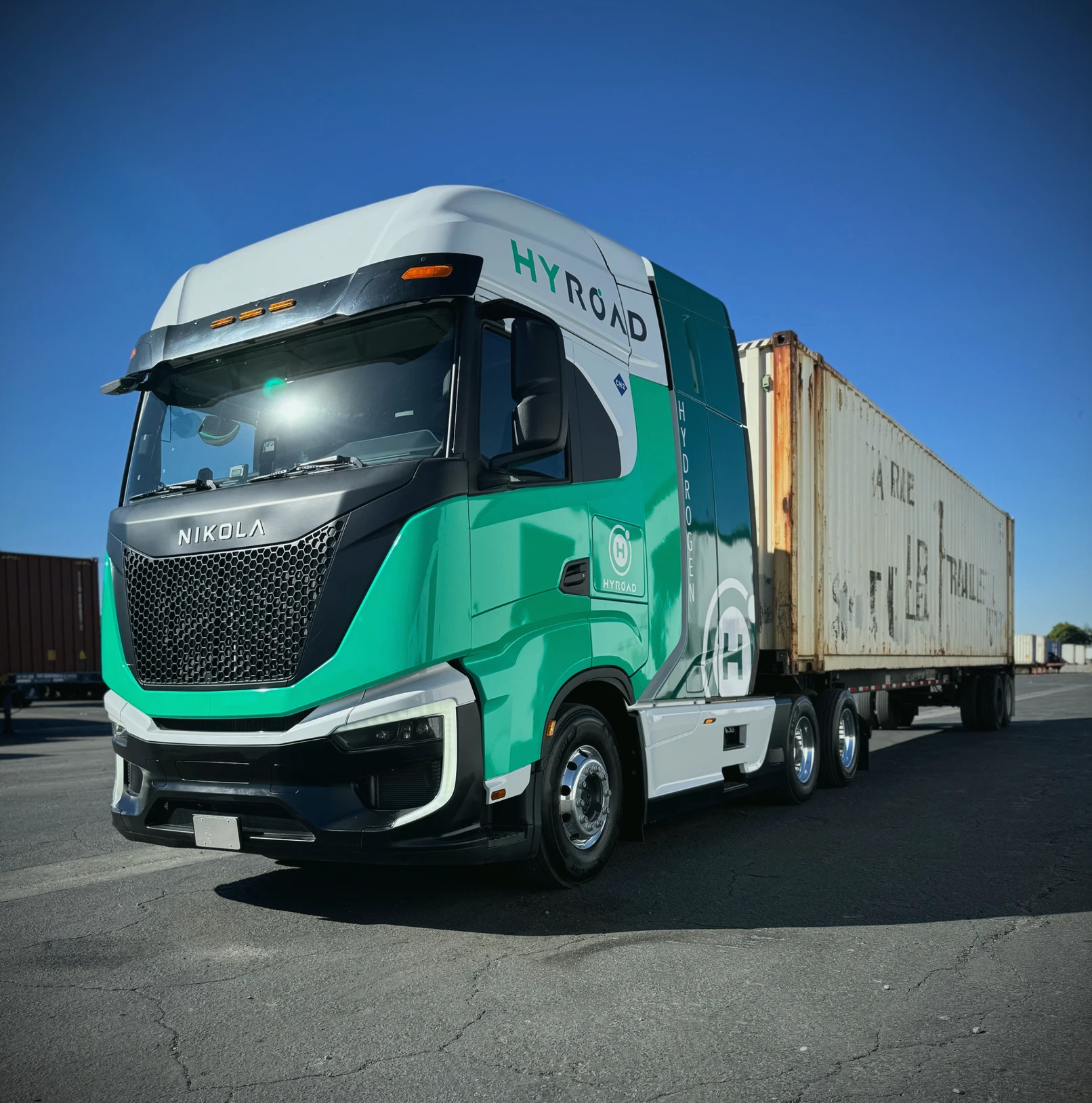 A hydrogen-powered Nikola Tre semi wrapped in a Hyroad Energy livery with a cargo trailer.