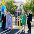 Four professionals at Mitra EV electric vehicle charging station launch event with blue balloons