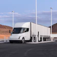 White Tesla Semi electric truck charging at a desert station with modern infrastructure
