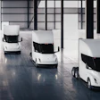 Four white Tesla Semi electric trucks parked in a modern warehouse interior