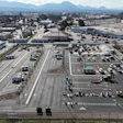 Aerial view of industrial complex with parking lots, warehouses, and mountains in background