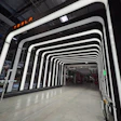 Modern Tesla manufacturing facility with neon-lit white tunnel architecture and industrial workspace