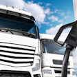 White commercial truck with EV charging cable connected, photographed outdoors against blue sky