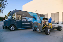 Harbinger Motors' battery-electric step van parked next to the naked truck chassis outside a warehouse.