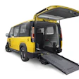 Yellow Kia PV5 electric van with rear wheelchair ramp deployed and rear door open