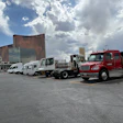 Commercial vehicles parked in lot with Encore casino and city skyline under cloudy sky
