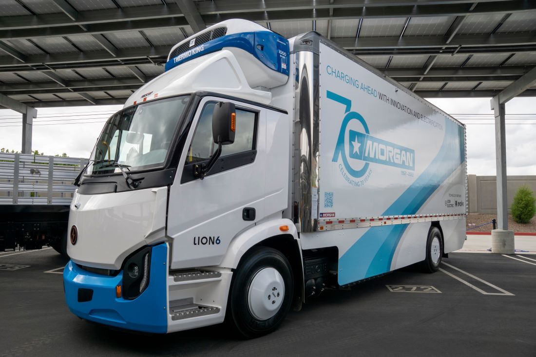 A Lion6 Class 8 battery-electric truck sits parked under a covered structure.