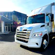 White Hino delivery truck parked in front of modern commercial building with glass facade