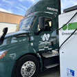 Green electric semi-truck with Nevova branding connected to GreenLane charging station