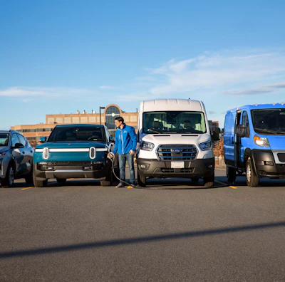 Battery-electric vehicles, including a Rivian, and two Ford E-Transits, receive charging from a SparkCharge mobile charger.
