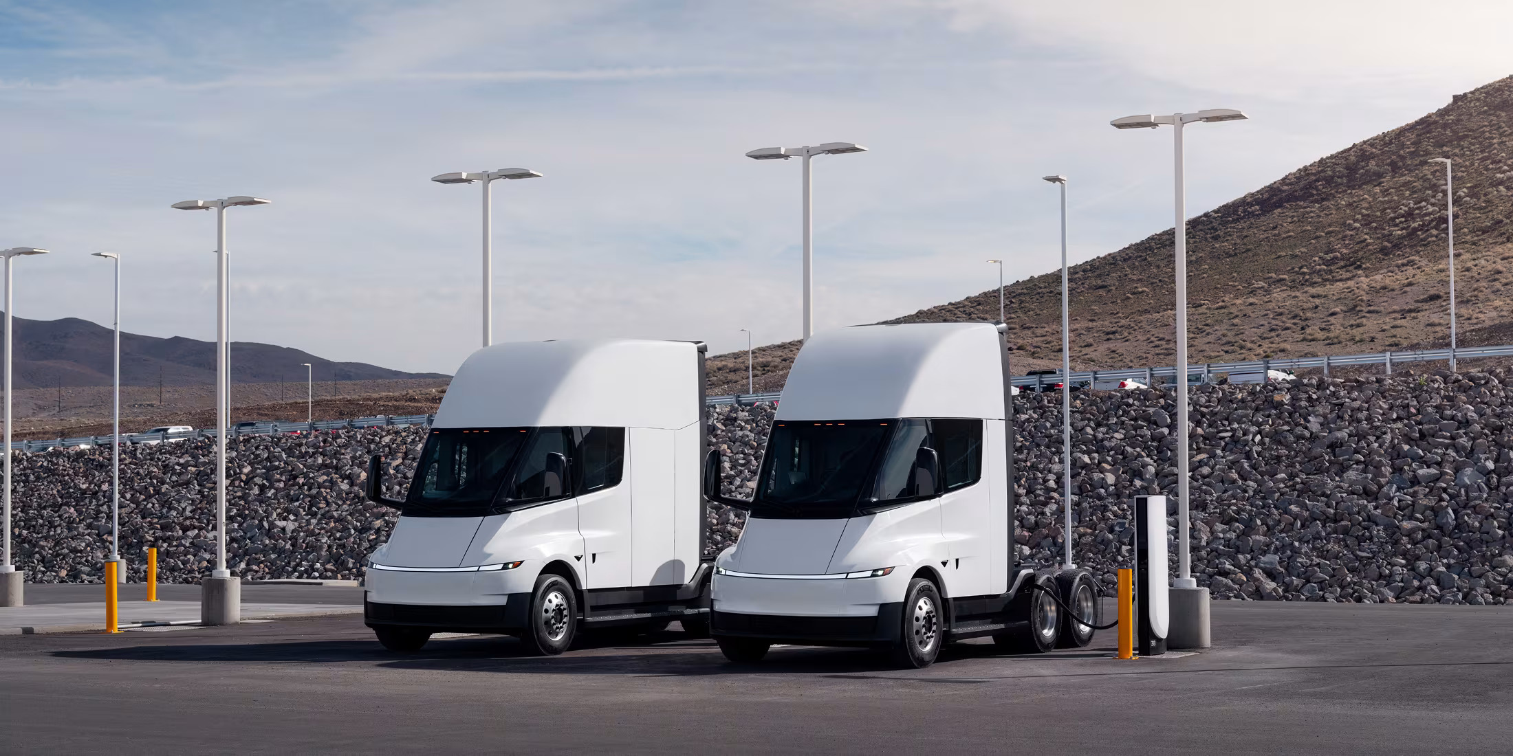 Two white Tesla Semis parked at a charging station.
