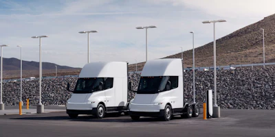 Two white Tesla Semis parked at a charging station.