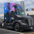 Black Schneider Electric branded semi-truck with blue and purple custom livery parked in urban commercial area
