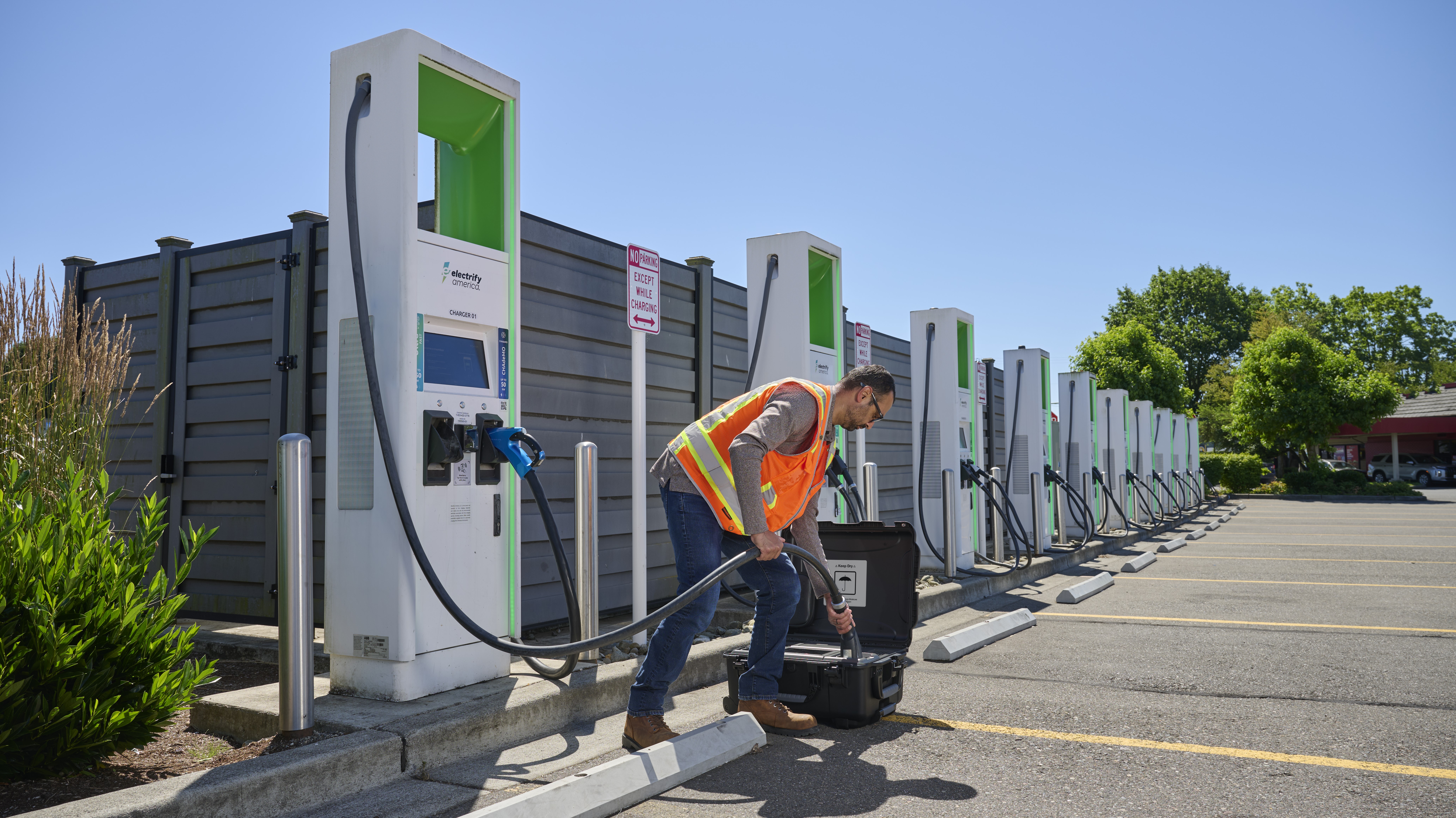 A worker connects the new Fluke FEV500 to a fast charger at a fleet charging depot.