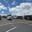 Commercial trucks parked in a lot under blue sky with white clouds