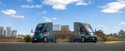 Two ArcBest-branded Tesla Semi trucks parked outside an ABF Freight facility.