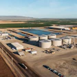 Aerial view of agricultural processing facility with storage tanks, warehouses, and equipment in rural landscape