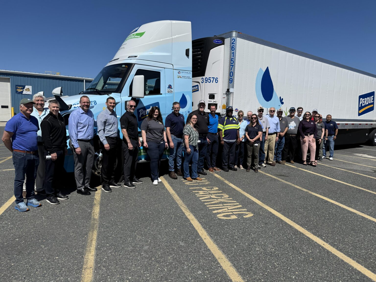 Employees from Optimus Technologies, Perdue Farms, and the Maryland Soybean Board stand in front of a biodiesel-powered Volvo semi-truck.