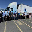 Large group of employees posing in front of a white Penske refrigerated delivery truck on a sunny day