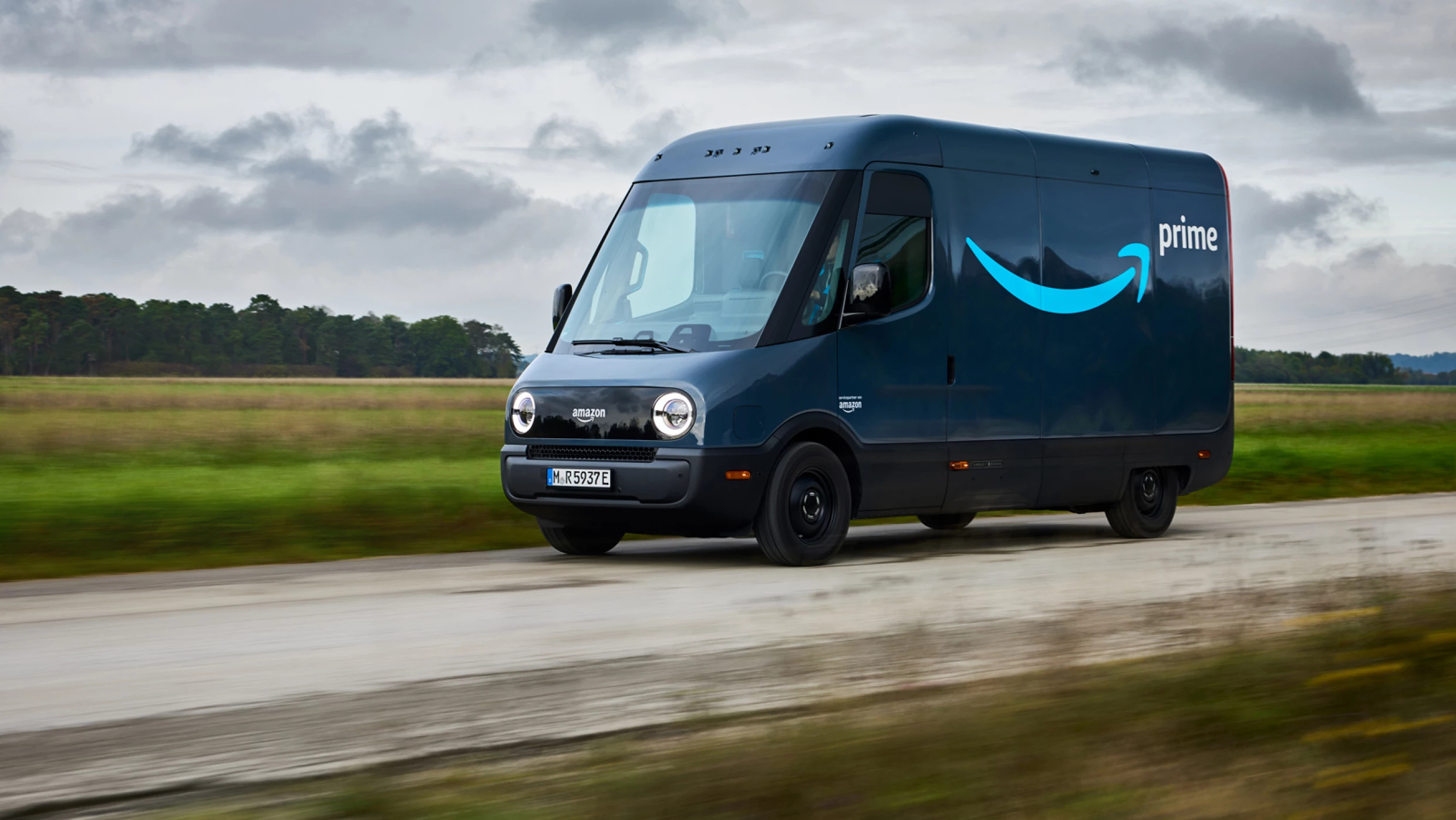 An Amazon Prime branded Rivian Electric Delivery Vehicle (EDV) driving a rural route in Europe.