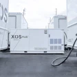 XOS Hub mobile electric vehicle charging station with charging cable deployed between two white branded trucks
