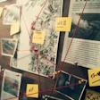 Investigation board with connected photos, maps, documents, and yellow notes linked by red string