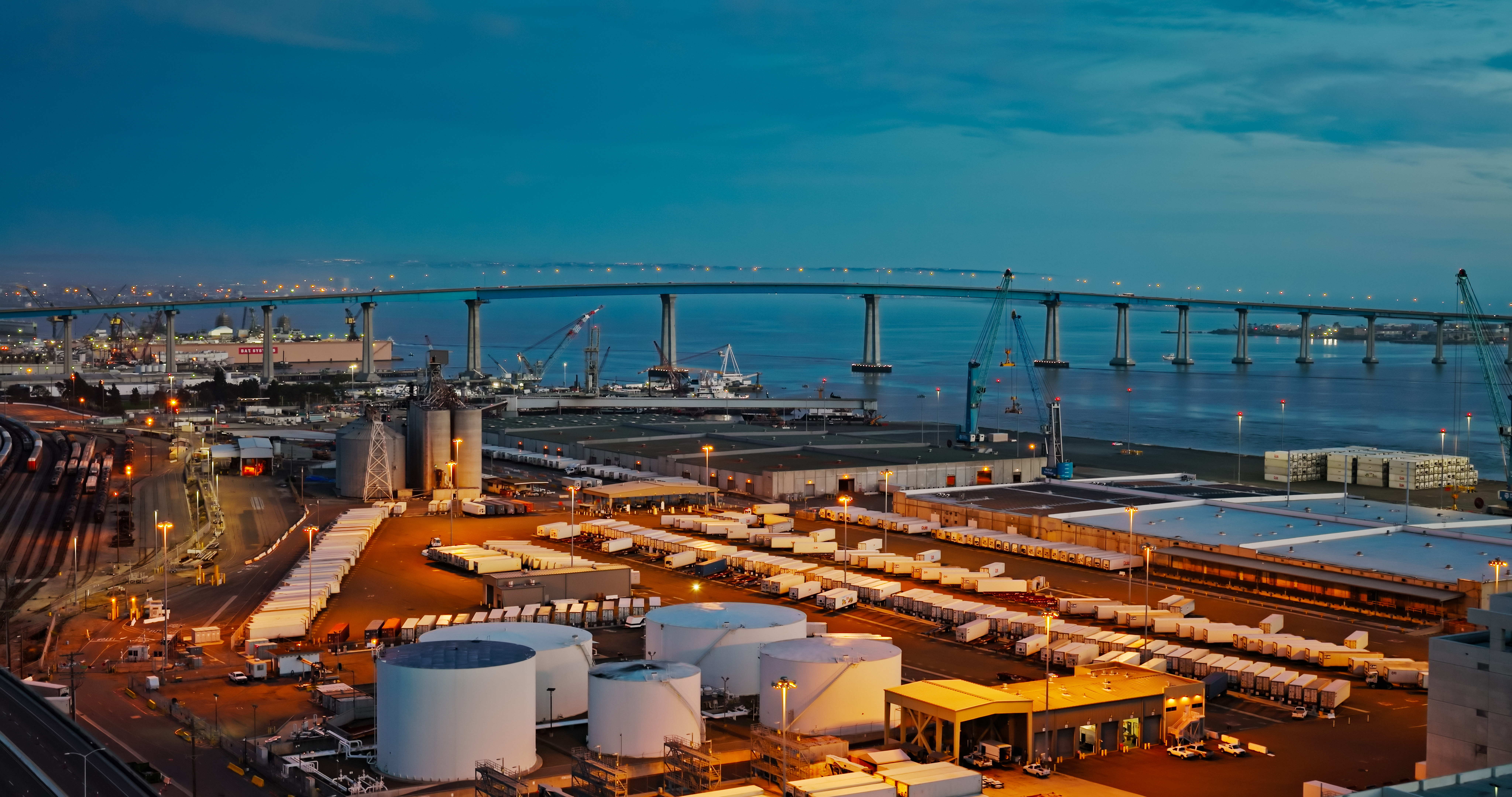 The Port of San Diego at dusk, with shipping containers and storage tanks visible throughout the terminal.