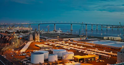 The Port of San Diego at dusk, with shipping containers and storage tanks visible throughout the terminal.