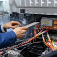 Technician in blue uniform inspecting electric vehicle battery and electrical components